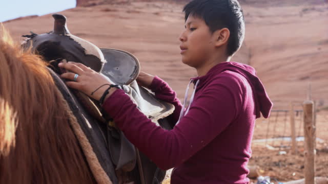 Young Navajo Girl Saddling up her Horse for a Ride Through Monument Valley