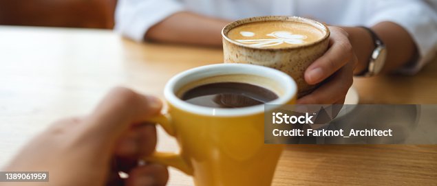 istock Closeup image of a young couple holding and drinking coffee together in cafe 1389061959