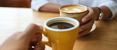 istock Closeup image of a young couple holding and drinking coffee together in cafe 1389061959