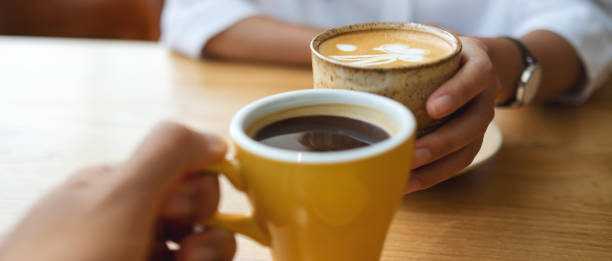 Closeup image of a young couple holding and drinking coffee together in cafe Closeup image of a young couple holding and drinking coffee together in cafe coffe to stock pictures, royalty-free photos & images