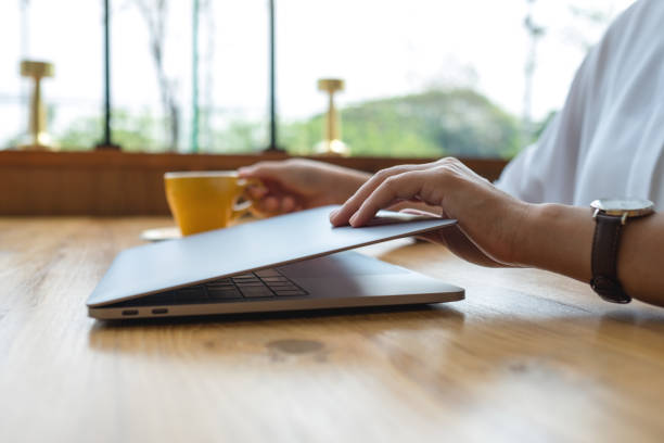 Closeup image of hands close or open a laptop computer on table after finished using it