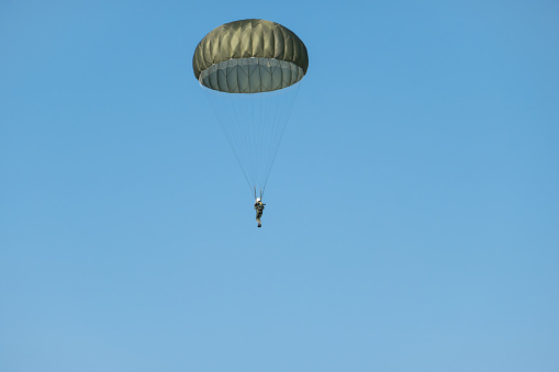 A person rises into the air attached to a parachute that is held above the water surface by a boat. Parasailing