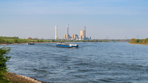 View towards the River Rhine in Orsoy, Germany Rheinberg, North Rhine-Westphalia, Germany - April 16, 2020: View at the River Rhine in Orsoy, with the Voerde power station in the background rheinberg illumination stock pictures, royalty-free photos & images