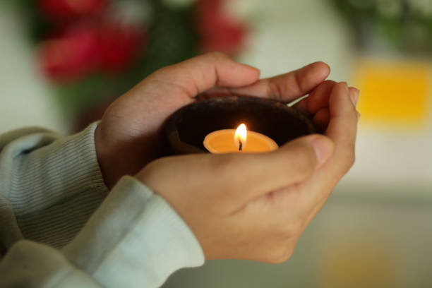 istock Candle light in a bowl on a young woman hands. 1389071998
