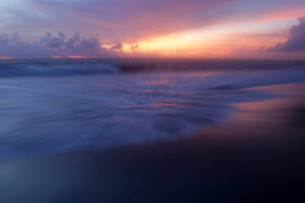 Sunset over the sea. Colorful sunset skyline with clouds with smooth waves water flow on the beach. Beautiful sunset sky background. Sunset sky clouds, wave and the sea. Nature landscape backgrounds.
