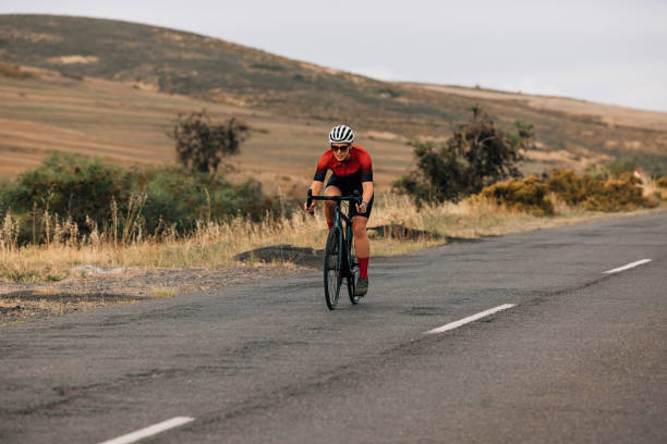 istock Professional female cyclist riding bicycle on a empty countryside road 1389073081