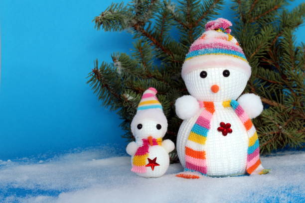 Two toy snowmen stand on a blue background.