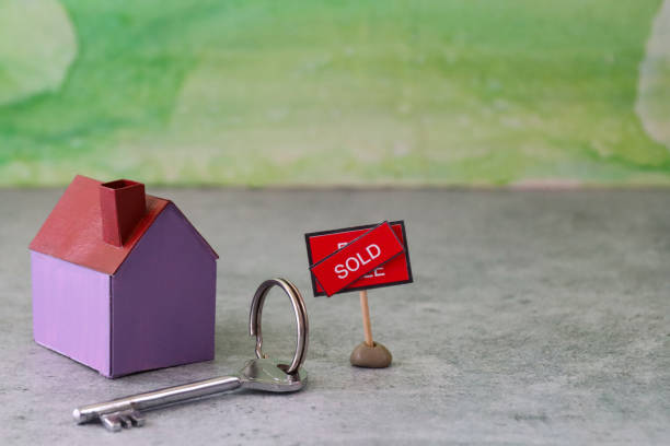 imagem de casa de papelão roxo além de uma chave no chaveiro, placa 'à venda' com diagonal ao lado do banner 'vendido' em texto, fundo verde manchado, imóveis e conceito de casa de mudança - row house house uk real estate sign - fotografias e filmes do acervo