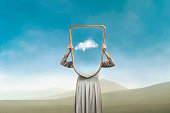 istock the woman hides holding a mirror in front of her face; introspection path concept 1389078062