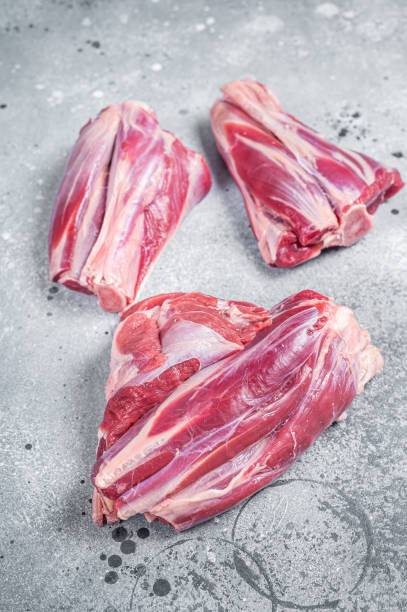 istock Uncooked Raw lamb shanks, mutton meat on kitchen table. Gray background. Top view 1389079755