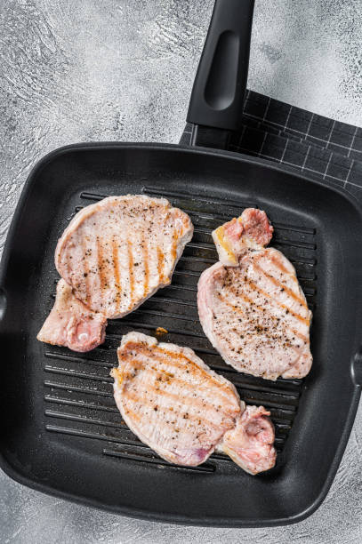 istock Fried on a grill skillet pork chop steaks. White background. Top view 1389082072