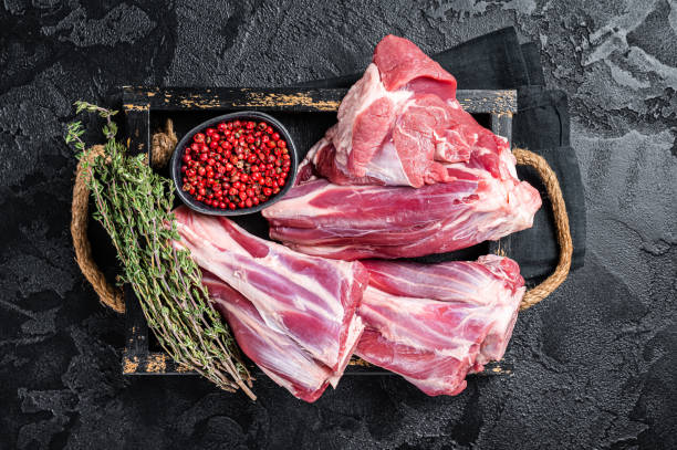 Fresh Raw lamb shanks with herbs and spices, mutton meat. Black background. Top view Fresh Raw lamb shanks with herbs and spices, mutton meat. Black background. Top view. lamb meat stock pictures, royalty-free photos & images