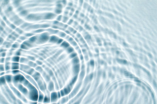 serum or cosmetic liquid drops falling on water surface abstract background. Beauty and skin care concept.