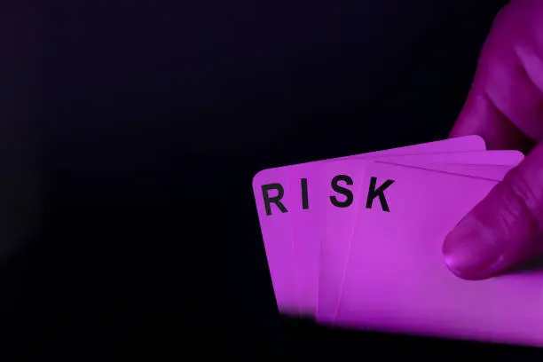Risk in Game and Real Life Concepts. Bet for Win. Close-up of Playing Card with text Risk. Dark tone with Red Light