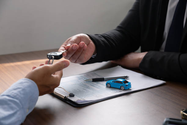 Young man receives a key from car salesman. After agreeing to a contract for rent or sale of a car at workshop. stock photo