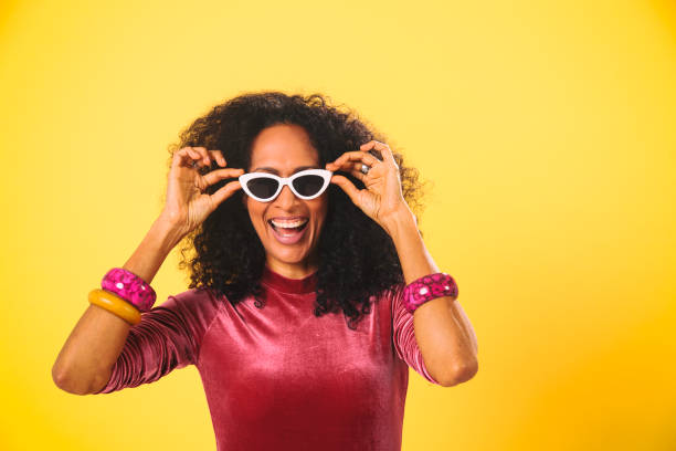 Latino woman with sunglasses on yellow background having fun. Color bacground series. Enjoying the summer.