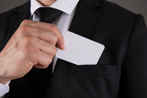 Business man takes out blank business card from pocket of his jacket