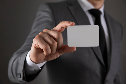 Businessman in gray suit showing his blank business card