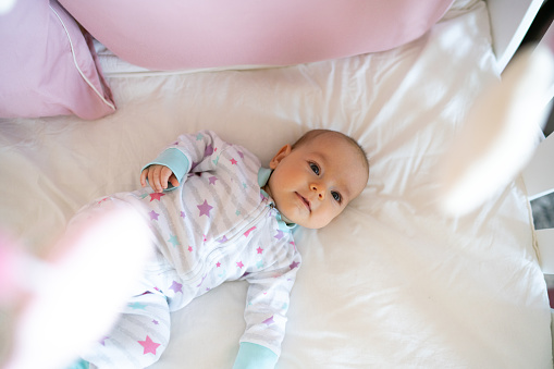 Smiling baby girl lying in crib