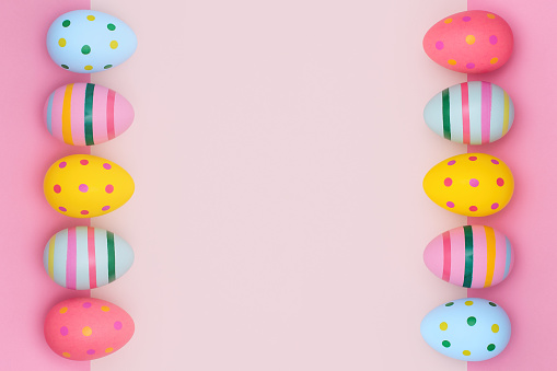 Easter two-sides border of vivid Easter eggs in retro style on a pink background. Multi-colored striped and dotted eggs in a rows with copy space.