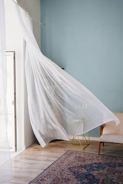 transparent fluttering curtain in the room with a candlestick on the table.