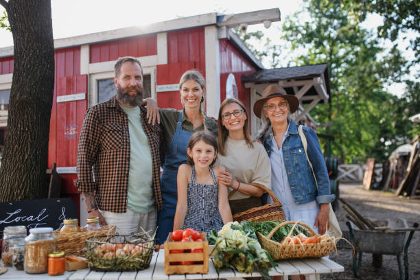 family of farmers selling homegrown products at community farmers market, looking at camera. - autarkie stockfoto's en -beelden