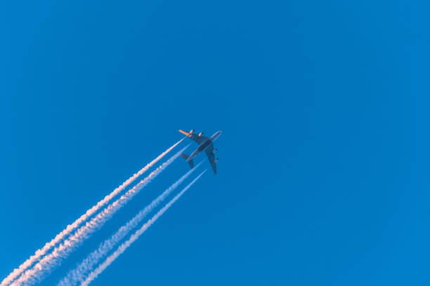 istock Airplane in a blue cloudless sky with colored colorful contrails without clouds during sunset and golden hour, Germany 1389102765