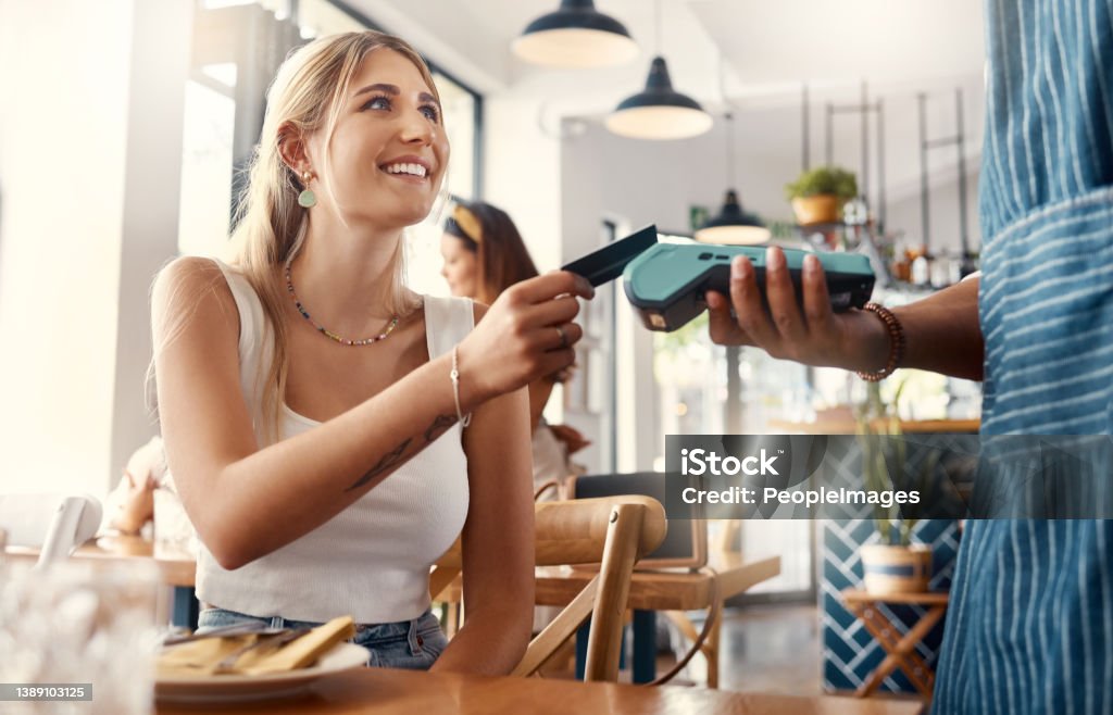 Shot of a young woman making a card payment using a nfc machine The convenience of online payments Credit Card Stock Photo