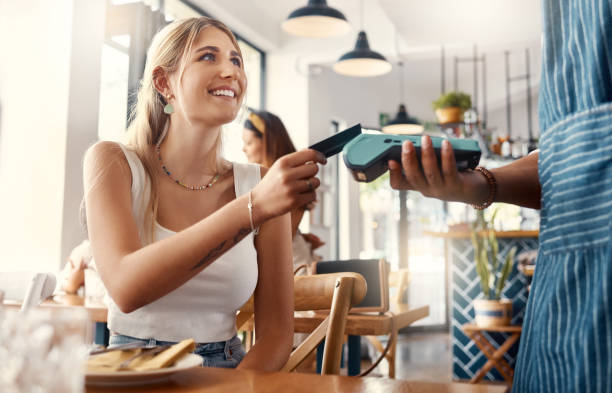 Shot of a young woman making a card payment using a nfc machine The convenience of online payments credit card stock pictures, royalty-free photos & images