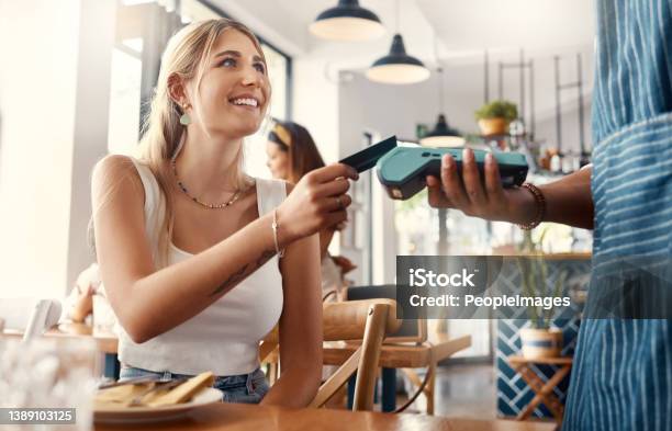 Shot Of A Young Woman Making A Card Payment Using A Nfc Machine Stock Photo - Download Image Now