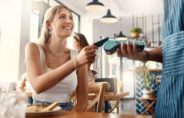 Photo of Shot of a young woman making a card payment using a nfc machine