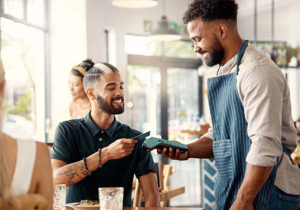 Shot of a young man using a nfc machine to make a card payment at a restaurant