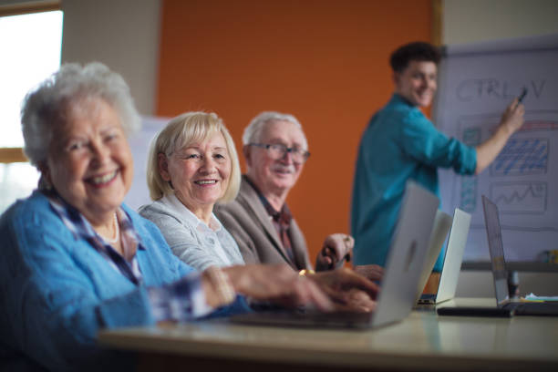 istock Senior group in retirement home with young instructor learning together in computer class 1389104104