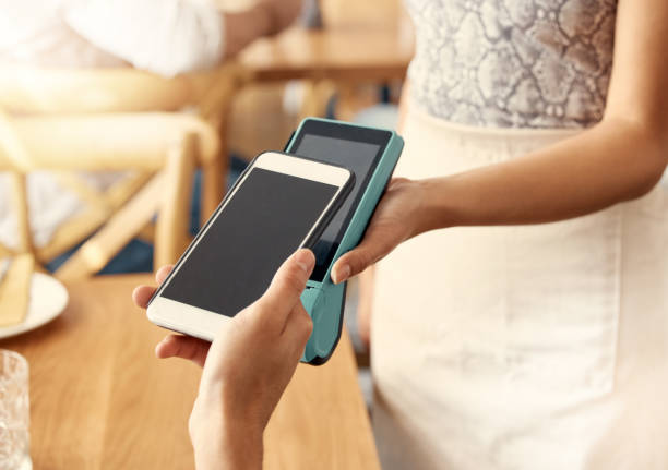 istock Shot of a customer making a payment using their smartphone and a nfc machine 1389104124