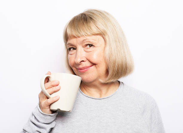 istock Old excited lady smiling laughing, holding cup drinking coffee, tea, beverage on white background 1389105343