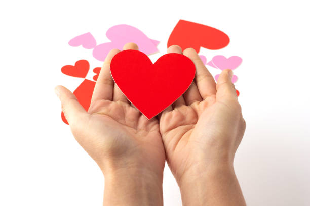 istock Red heart shaped paper craft place on hand isolated on a white background. 1389107986
