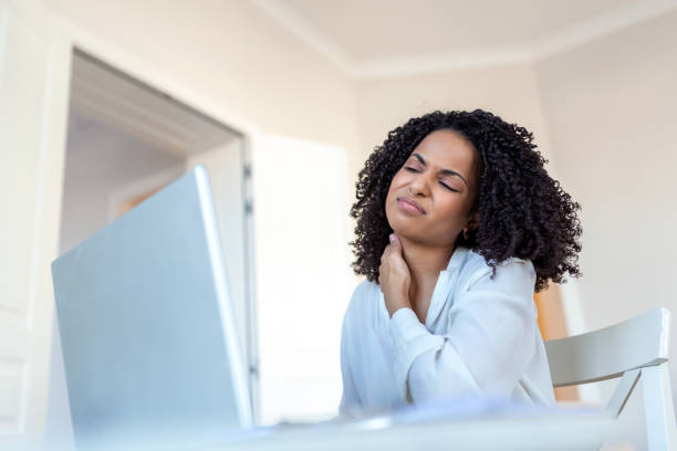istock Feeling exhausted. Frustrated young woman looking exhausted and massaging her neck while sitting at her working place 1389117961