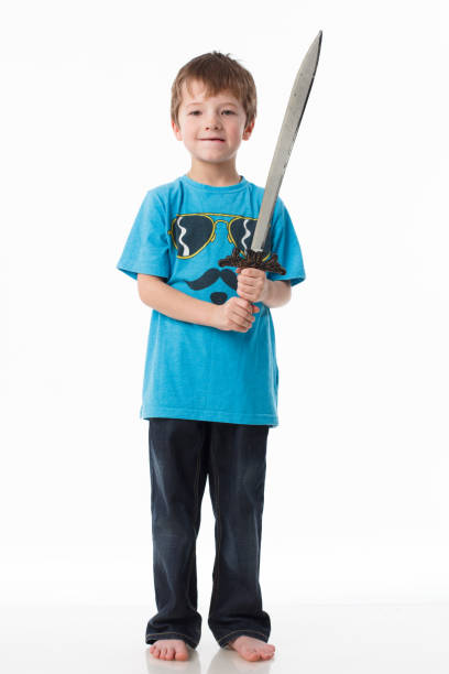 istock A little boy poses with a sword in a studio on a gray background. 1389118500