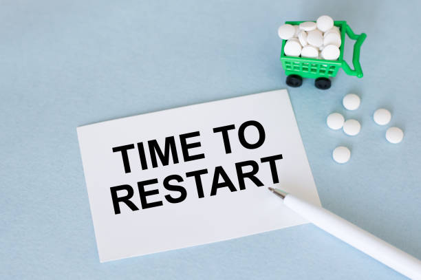 istock text TIME TO RESTART on a white card on a blue background next to a pen and white tablets, medical concept 1389120659