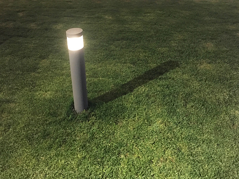 Outdoor garden lamp with grass texture with copy space at night