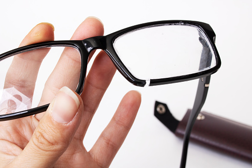 Broken glasses in hand on a gray background close up