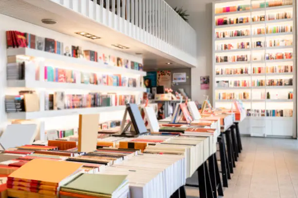 A bookstore very bright and modern with white shelves full of books seen during day light.
