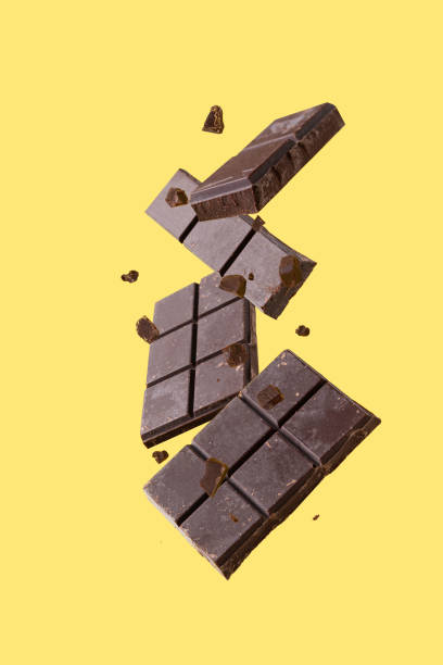 pieces of dark chocolate flying on a yellow background
