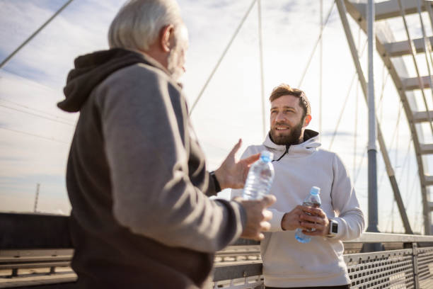 istock Mature and young man jogging on a bridge taking talking 1389127935
