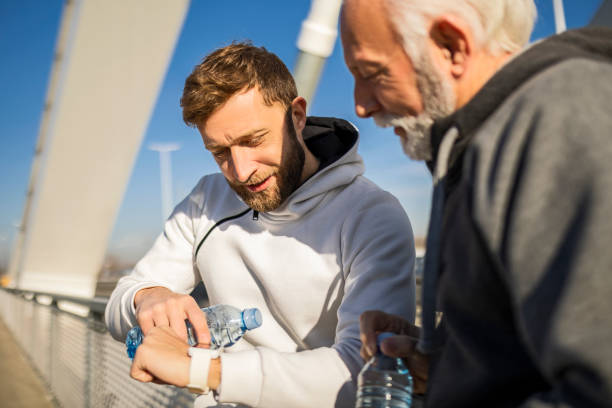 istock Mature and young man jogging looking at smart watch 1389127940