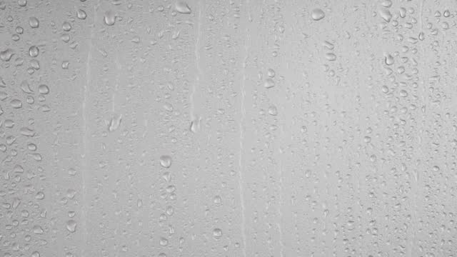 Water droplets flowing on gray background.