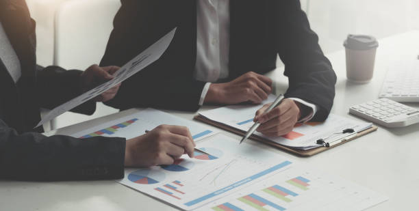 istock Business man holding a pen and analysis documents on office table with laptop computer and graph financial diagram working in the background. 1389133060