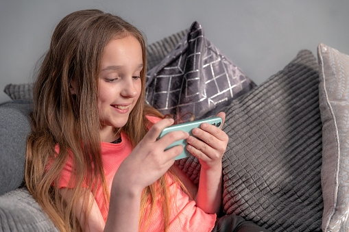 Girl uses a smartphone, sat on a sofa