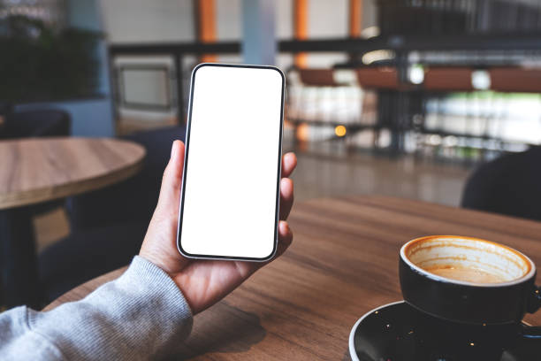 istock Mockup image of hands holding mobile phone with blank desktop screen in cafe 1389134926