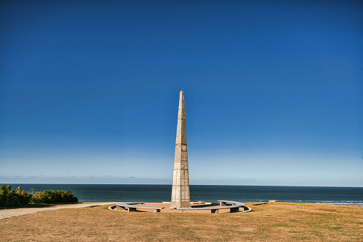 Omaha Beach, Colleville-sur-Mer, France, September 01, 2019:  Looking at the 1st US Infantry Division Memorial at Omaha Beach, Colleville-sur-Mer, Calvados, Normandy, France. The obelisk stands in the middle of the area of Wiederstandsnest (WN62). WN62 was one of the strongest defending positions in that area. The WN62-area is dotted with casemates, tobruks, trenches and other defense objects.